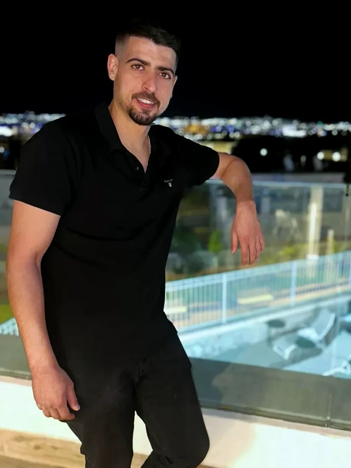 נאור סייג, מייסד מדיקל ספא, בחולצה שחורה על מרפסת מול אורות אילת בלילה