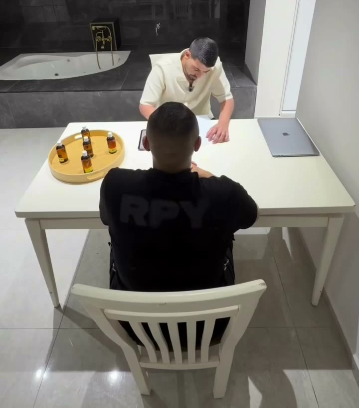 נאור יושב עם מטופל לשיחת התאמה ליד שולחן עם בקבוקי שמנים